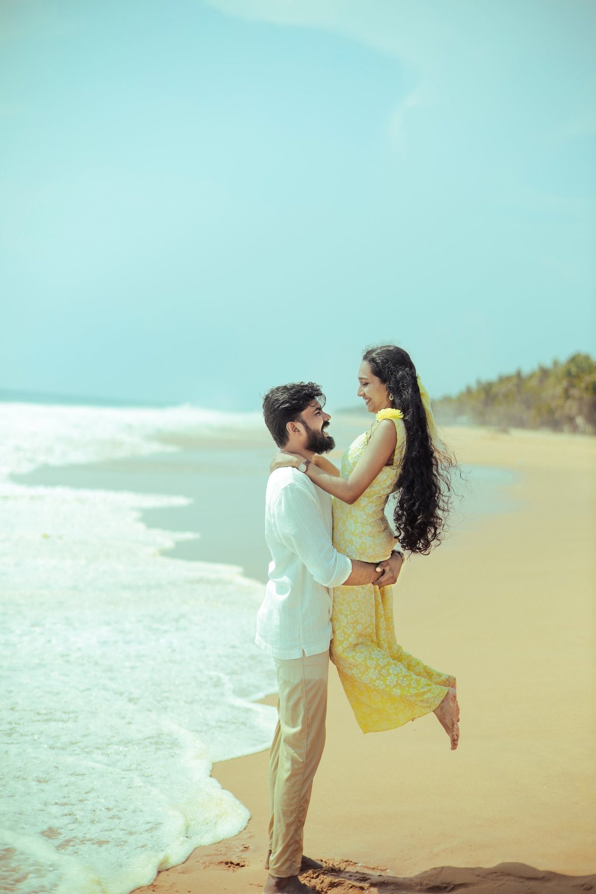 Abhinand lifting Akshaya on a sunny beach