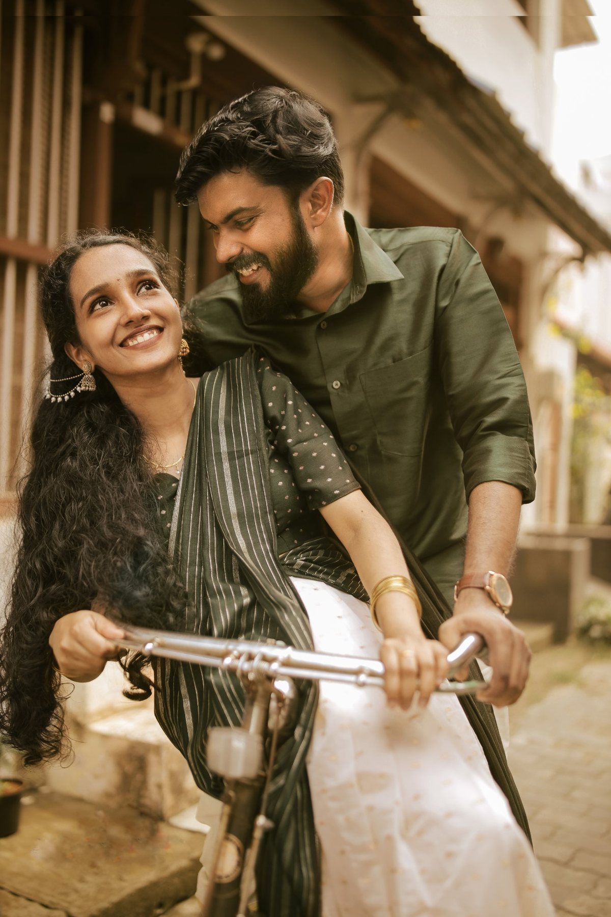 Akshaya smiling on a bicycle with Abhinand beside her