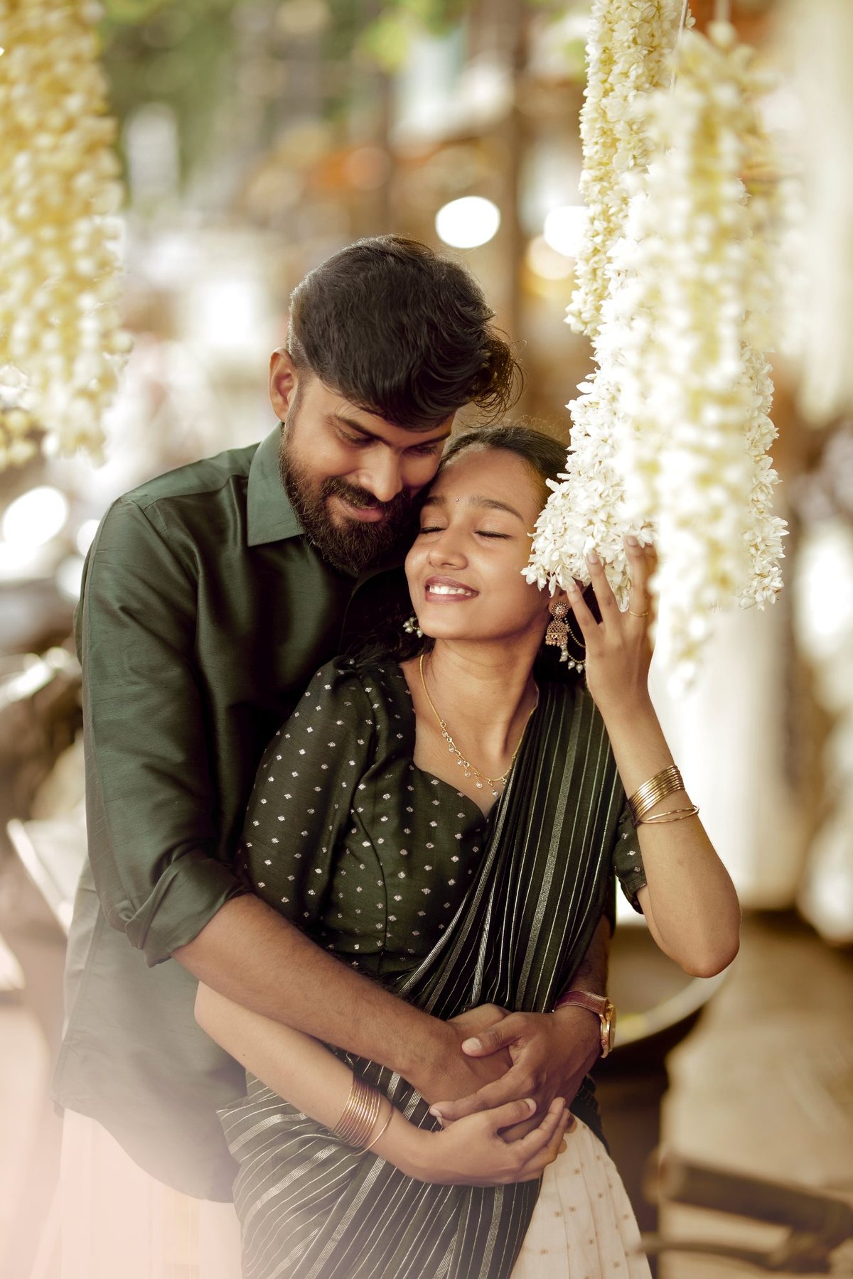 Abhinand embracing Akshaya among hanging jasmine garlands