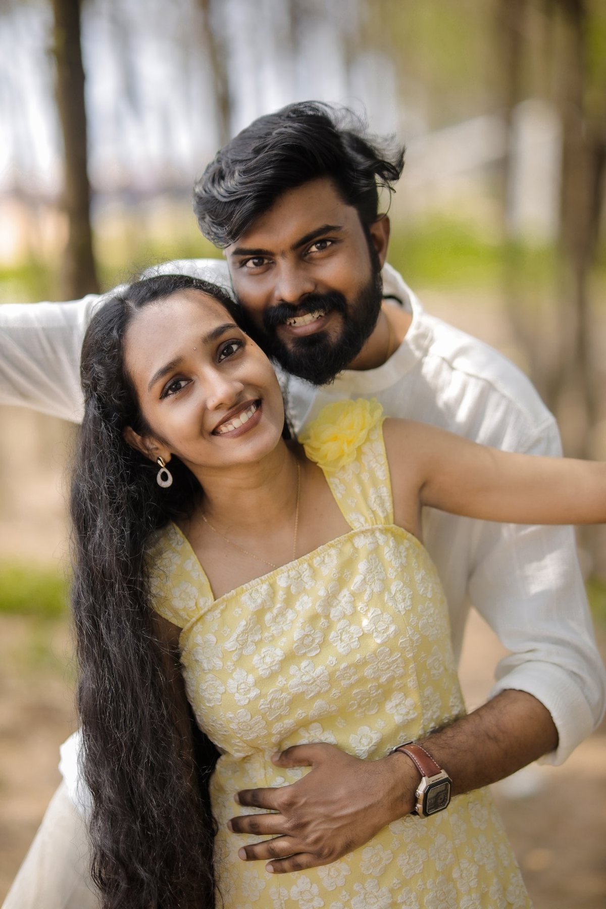 The couple embracing outdoors, Akshaya in a yellow dress